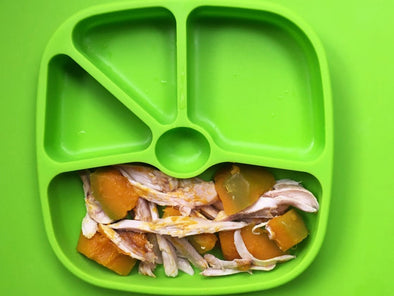 chicken with pumpkin pieces for baby led weaning on a silicone plate and placemat